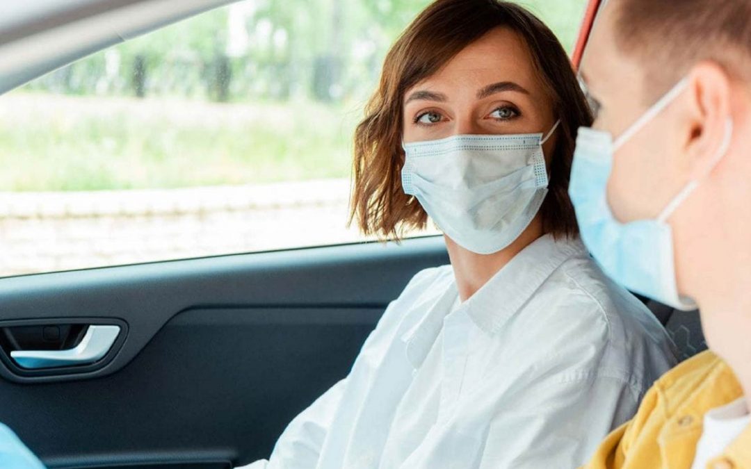 2 people wearing masks in a car